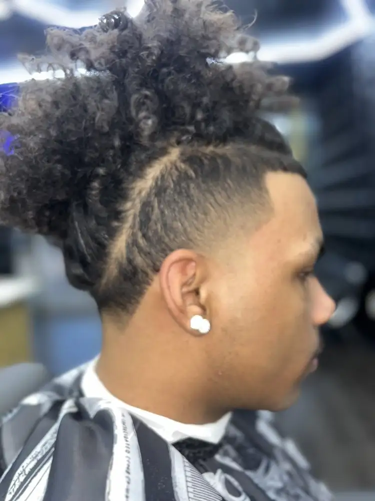 A curly top knot with a shaved line design, side view