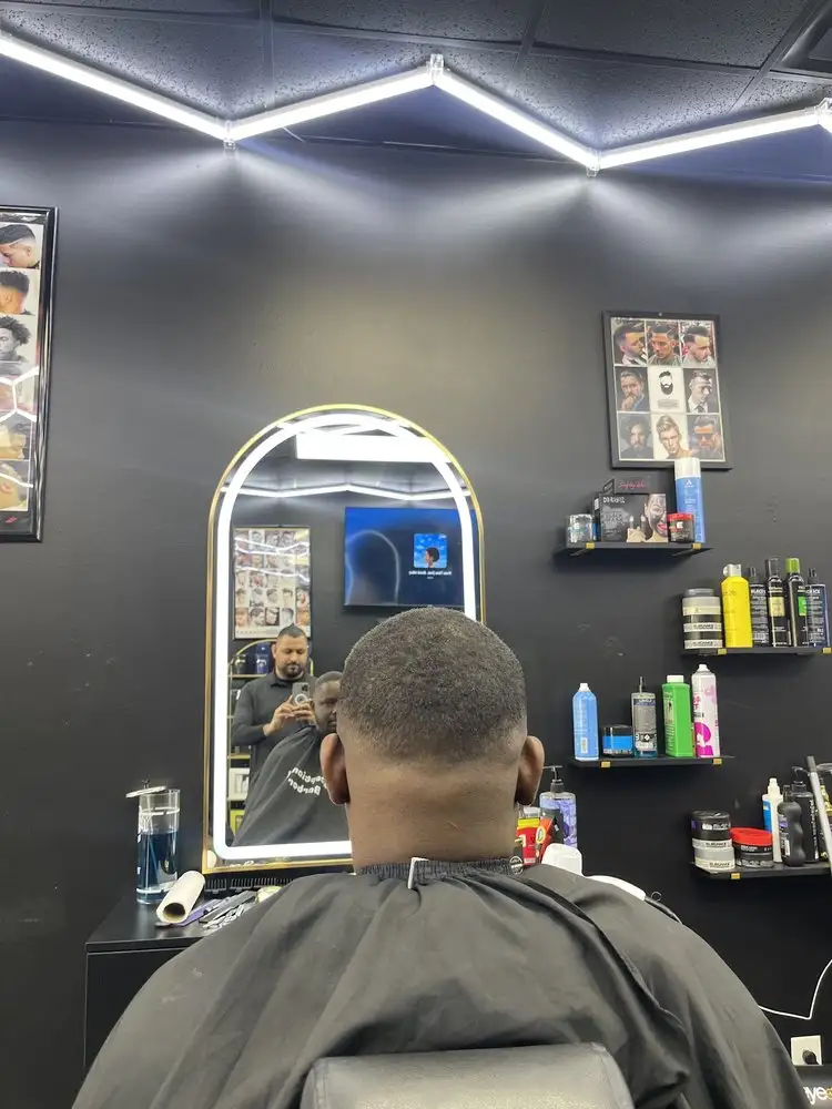 A client in the chair facing a lit, arched mirror