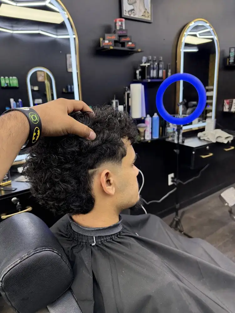 A barber checking a curly cut under a ring light