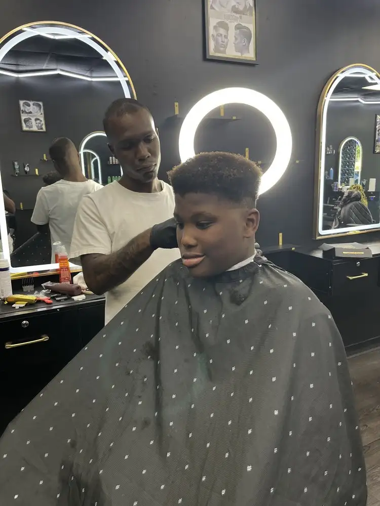 A barber working on a fade under a ring light